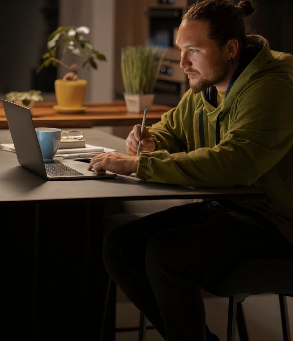 homem sentado na cadeira olhando para o notebook na mesa